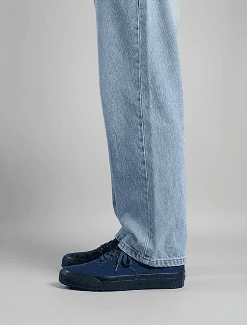AI model in light blue jeans wearing navy canvas sneakers, close-up on the feet, generated with Veeton