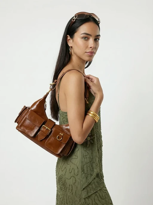 AI model in a green dress carrying a glossy tan leather shoulder bag with buckles, generated with Veeton