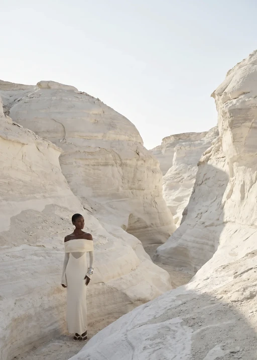 AI model in a cream off-shoulder maxi dress walking through a white rock canyon, generated with Veeton