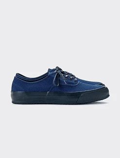 Packshot of a navy canvas low-top sneaker in side view before on-model generation