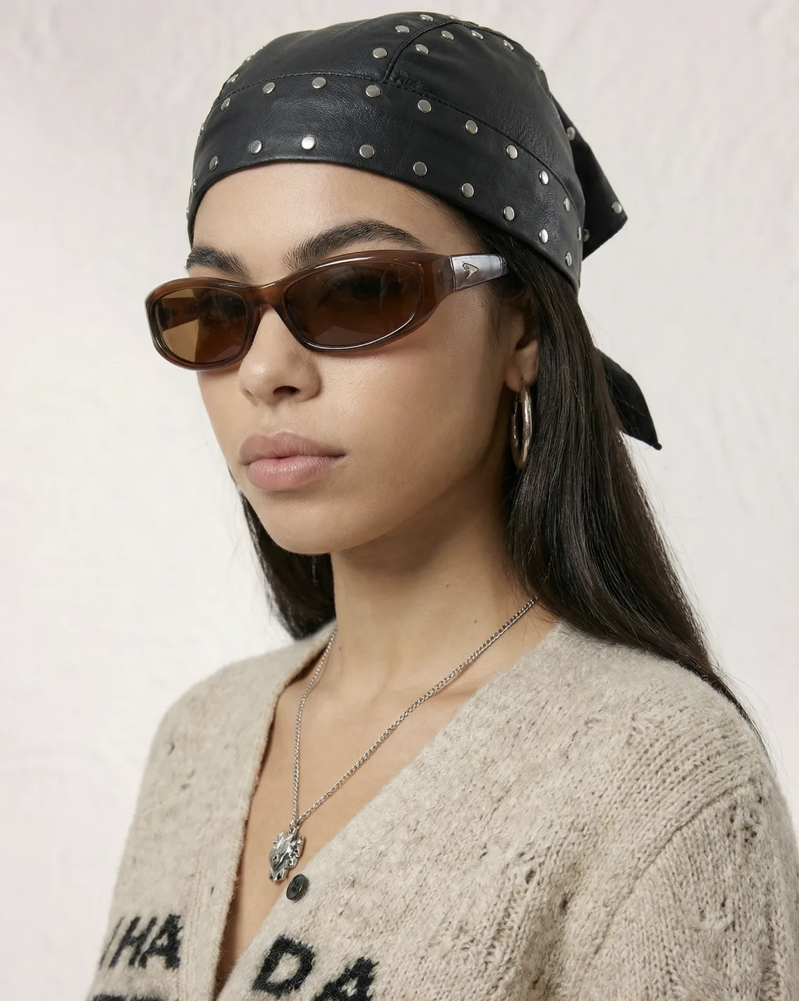 AI model in a studded black leather bandana, brown sunglasses and beige cardigan, studio shot generated with Veeton