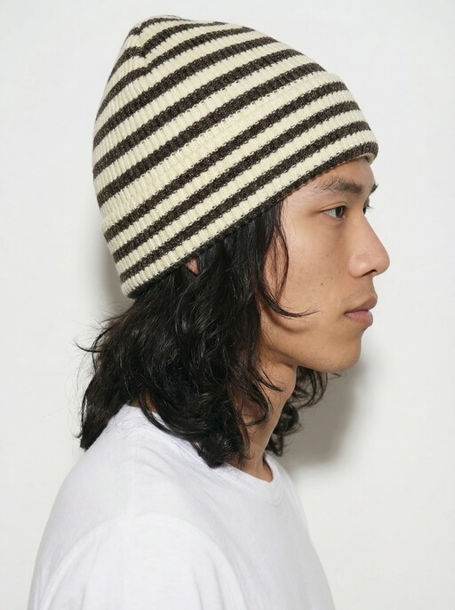 AI model in profile wearing a cream and brown striped ribbed beanie, generated with Veeton