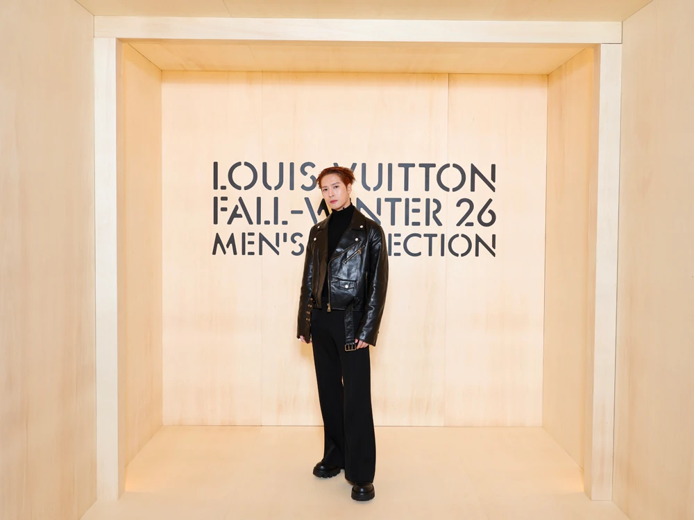 Man in a black leather biker jacket and trousers posing in a wooden set at the Louis Vuitton Fall-Winter 26 men's show