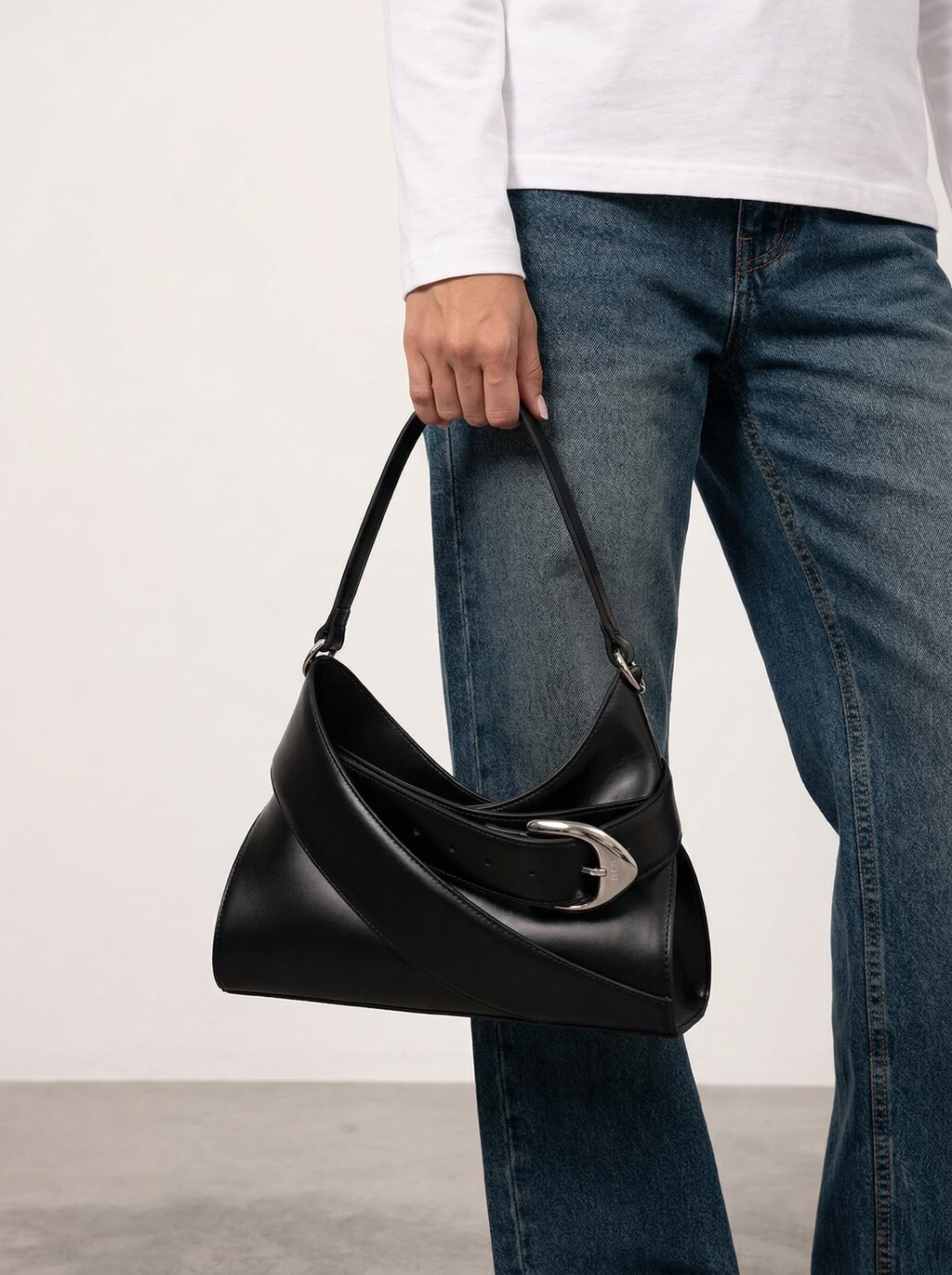 AI model in a white top and jeans holding a black leather shoulder bag with silver buckle, generated with Veeton