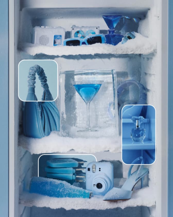 Monochrome ice-blue still life: frosted freezer shelves with a blue handbag, cocktail, sunglasses, camera and heels